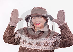 Cheerful middle-aged woman in a warm winter brown hat, sweater and mittens with raised hands. An active lifestyle in the winter