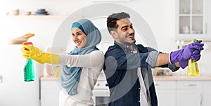 Cheerful middle-eastern husband and wife cleaning kitchen, panorama