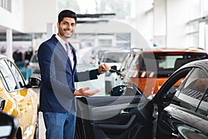 Cheerful middle eastern sales manager showing nice car