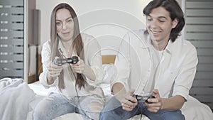 Cheerful millennial couple playing video games indoors. Portrait of joyful young Caucasian man and woman using game