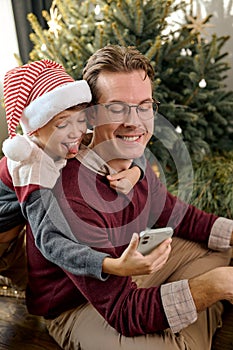cheerful millennial father having fun laughing with adorable little kid son,taking photo