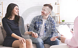 Cheerful millennial spouses smiling to each other at consultation