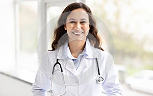 Cheerful millennial woman general physician standing by window