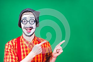 Cheerful mime posing near a green background