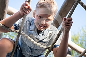 Cheerful and mischievous boy making faces and looking at camera while playing on playground.