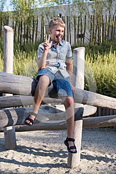 Cheerful and mischievous boy making faces while playing on playground.
