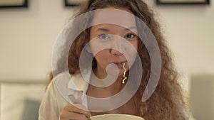 Cheerful mixed race lady with curly hair eats noodles