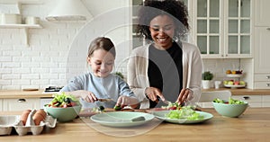 Cheerful mixed-race mom and daughter giving high five in kitchen