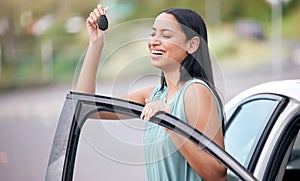 A cheerful mixed race woman holding keys to her new car. Hispanic woman looking happy buying her first car or passing