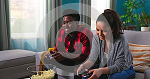 Cheerful mixed-races couple African American Man and Caucasian woman resting in room sitting on sofa