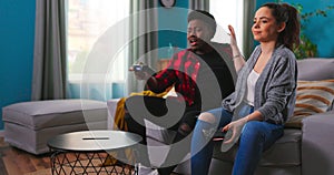 Cheerful mixed-races couple African American Man and Caucasian woman resting in room sitting on sofa