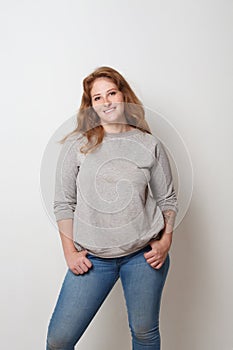 Cheerful model woman standing against white wall background, studio portrait