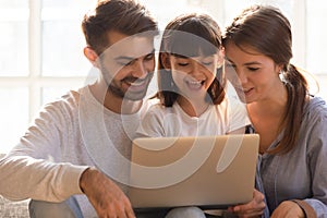 Cheerful mom dad and kid daughter using laptop at home