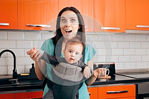 Happy Mother Holding Baby In Carrier in The Kitchen photo