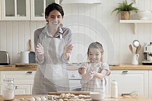 Cheerful mom and kid having fun, making mess in kitchen