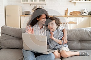 Mom and little kid greeting during video call on laptop wave hands to computer webcam smiling to dad