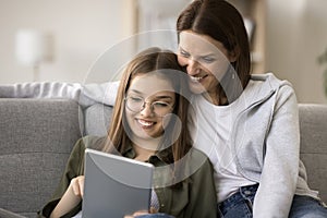 Cheerful mom and schoolgirl daughter in glasses using online service