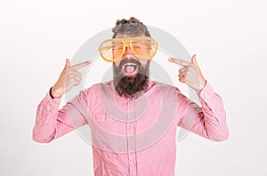 Cheerful mood concept. Hipster looking through of giant striped sunglasses.Man with beard and mustache on happy face