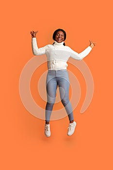 Cheerful Mood. Happy Young Black Woman Jumpinmg In Air With Raised Hands