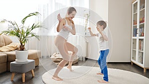 Cheerful mother and 6 year old son dancing at home together. Family having fun together, listening music, active lifestyle,