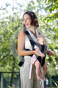 Cheerful mother with baby in sling