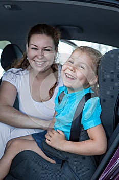 Cheerful mother with daughter sitting in car seat