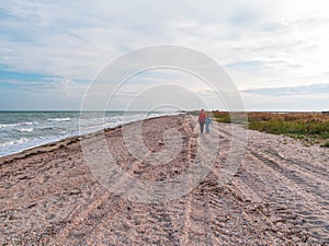 Cheerful mother and daughter walking running on sea beach. Happy family. Cute little child playing with mom outdoors