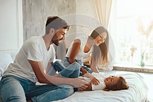 Cheerful mother and father playing with a kid indoors