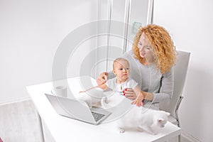 Cheerful mother with her baby playing with pet in the living room