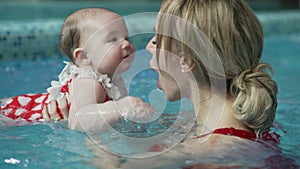 Cheerful mother with her baby in the pool