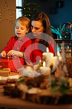 Cheerful mother packing christmas presents with her son