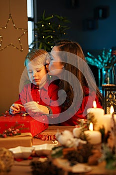 Cheerful mother packing christmas presents with her son