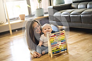 Cheerful mother playing with his baby girl on floor at living room