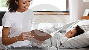 Cheerful Mother Reading Story to Her Child in Bed