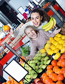 Cheerful mother and smiling little girl choosing fresh fruits