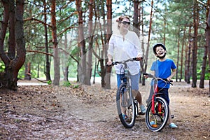 Cheerful mother and son riding a bicycle in forest
