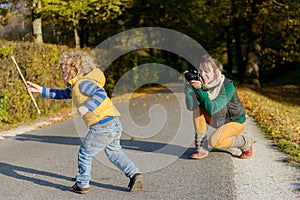 Cheerful mother taking picture of her cute little