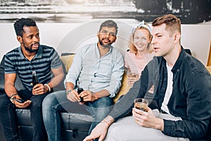 Cheerful multi-ethnic friends sitting on sofa