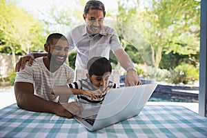 Cheerful multi-generation family using laptop at porch