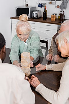 cheerful multicultural pensioners playing tower wood