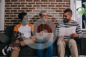 cheerful multicutural businessmen sitting on sofa