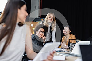 cheerful multiethnic businesswomen looking at blurred