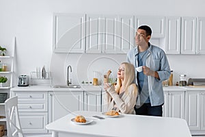 cheerful multiethnic couple with coffee cups