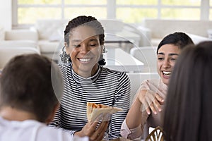 Cheerful multiethnic girls chatting and laughing, eating pizza in pizzeria