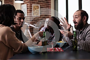 Cheerful multiethnic group of friends sitting at home while playing boardgames together.