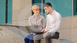 Cheerful multiethnic multiracial couple colleagues arabic hispanic man and caucasian woman standing near business center