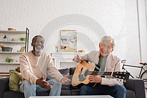Cheerful multiethnic pensioners with acoustic guitar