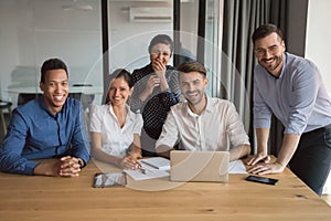 Cheerful multiethnic professional business team posing together at office table