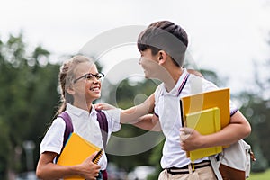 Cheerful multiethnic schoolkids with notebooks looking