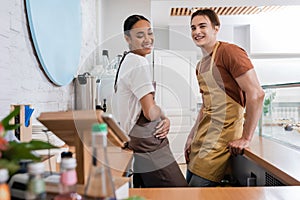 Cheerful multiethnic sellers in aprons standing